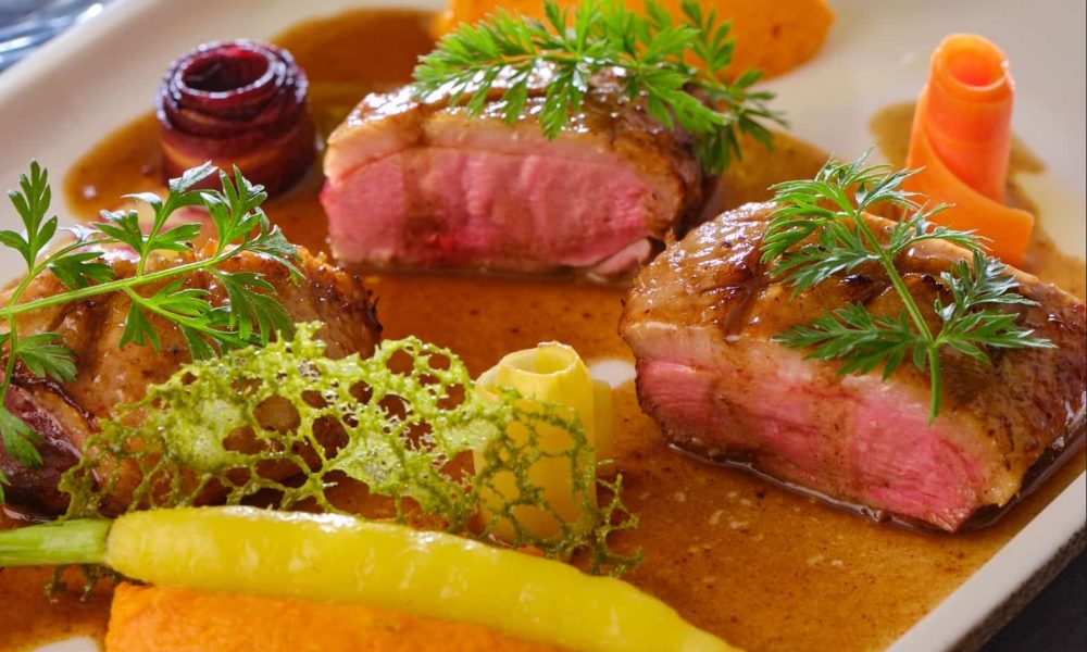 Filet de canard rôti au sang, jus de canard à l’ail noir et mousseline des sables, carottes glacées et tuile de fanes